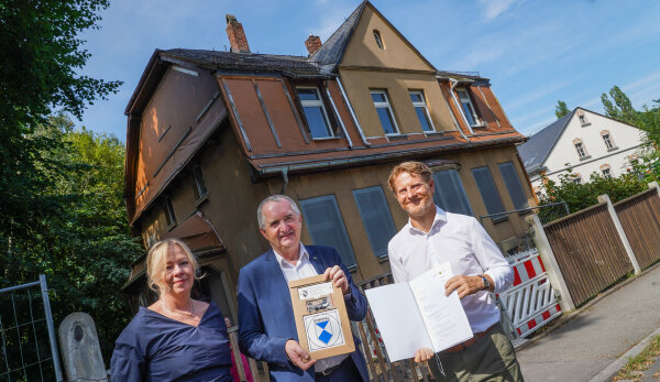 Thomas Schmidt, der Staatsminister für Regionalentwicklung, Kulturbürgermeisterin Dagmar Ruscheinsky und Baubürgermeister Michael Stötzer stehen vor dem Karl Schmidt-Rottluff-Haus. Alle sind förmlich gekleidet und lächeln in die Kamera. Die Sonne scheint.