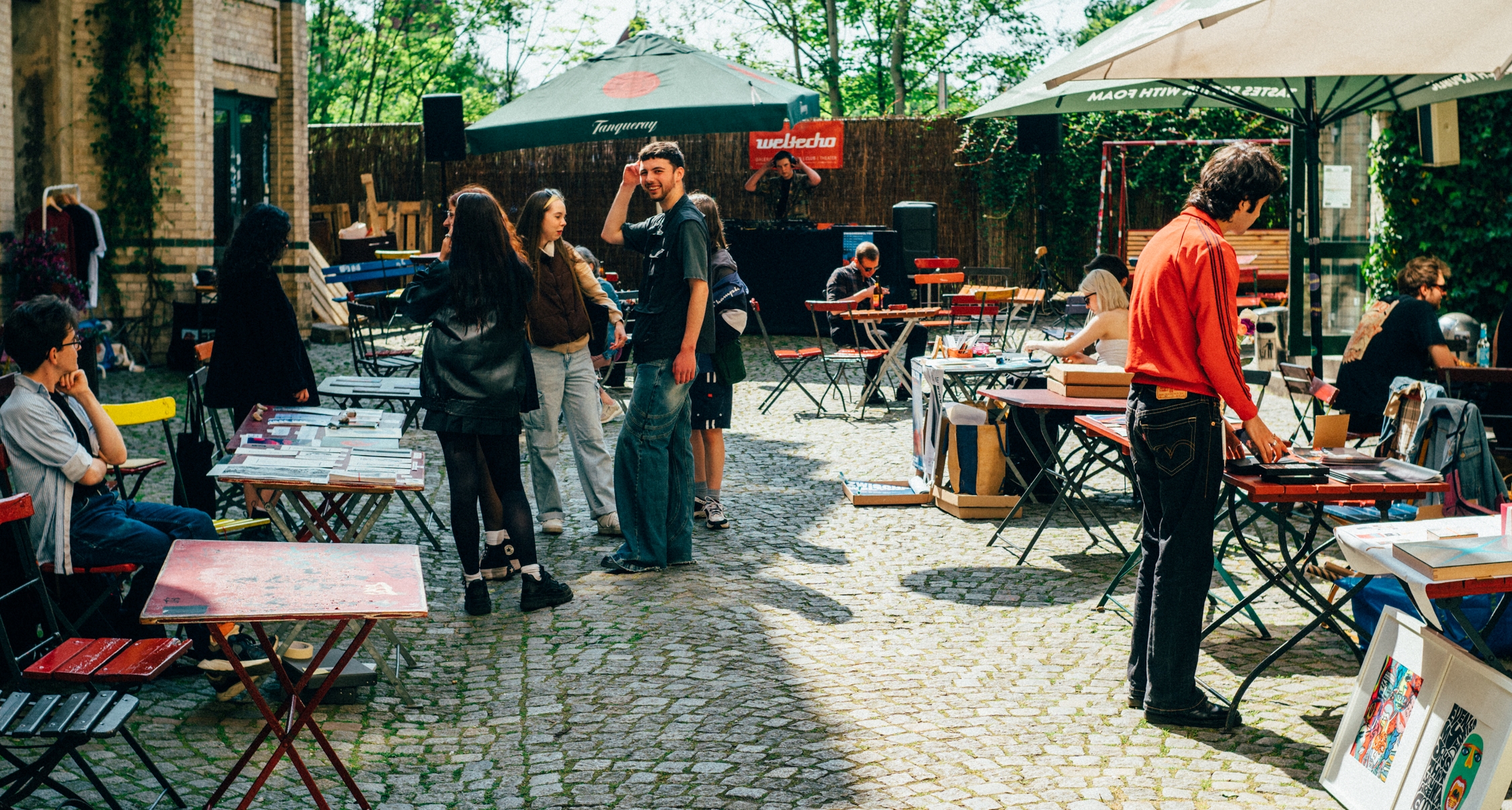 Junge Menschen, bunte Tische und Stühle im Innenhof des Weltechos